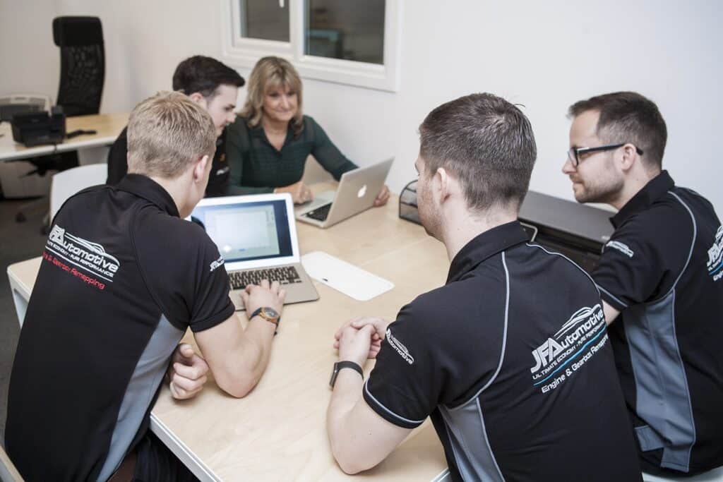 The JF Automotive office team at a desk with laptops, working through customer enquiries