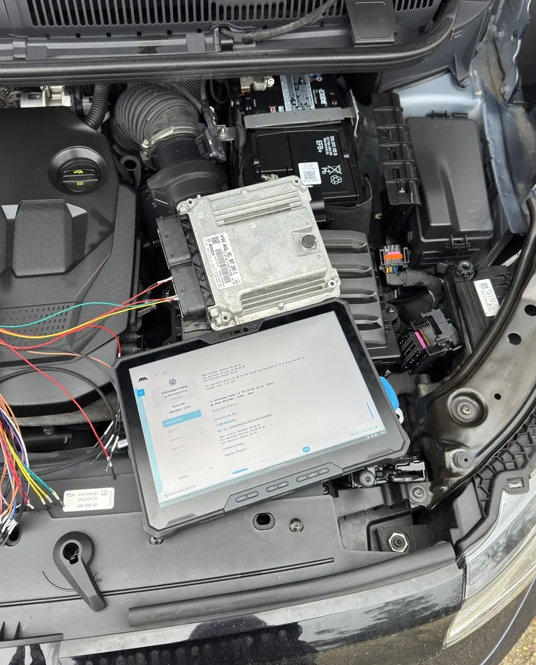 A Volkswagen Caddy 2.0 TDI van with its ECU removed and our programming rig connected, being remapped on a driveway in Kent.